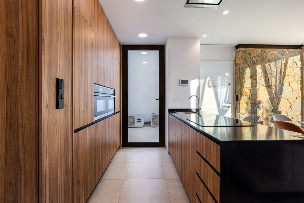 Kitchen with a full-height natural wood panelled wall and integrated cabinetry