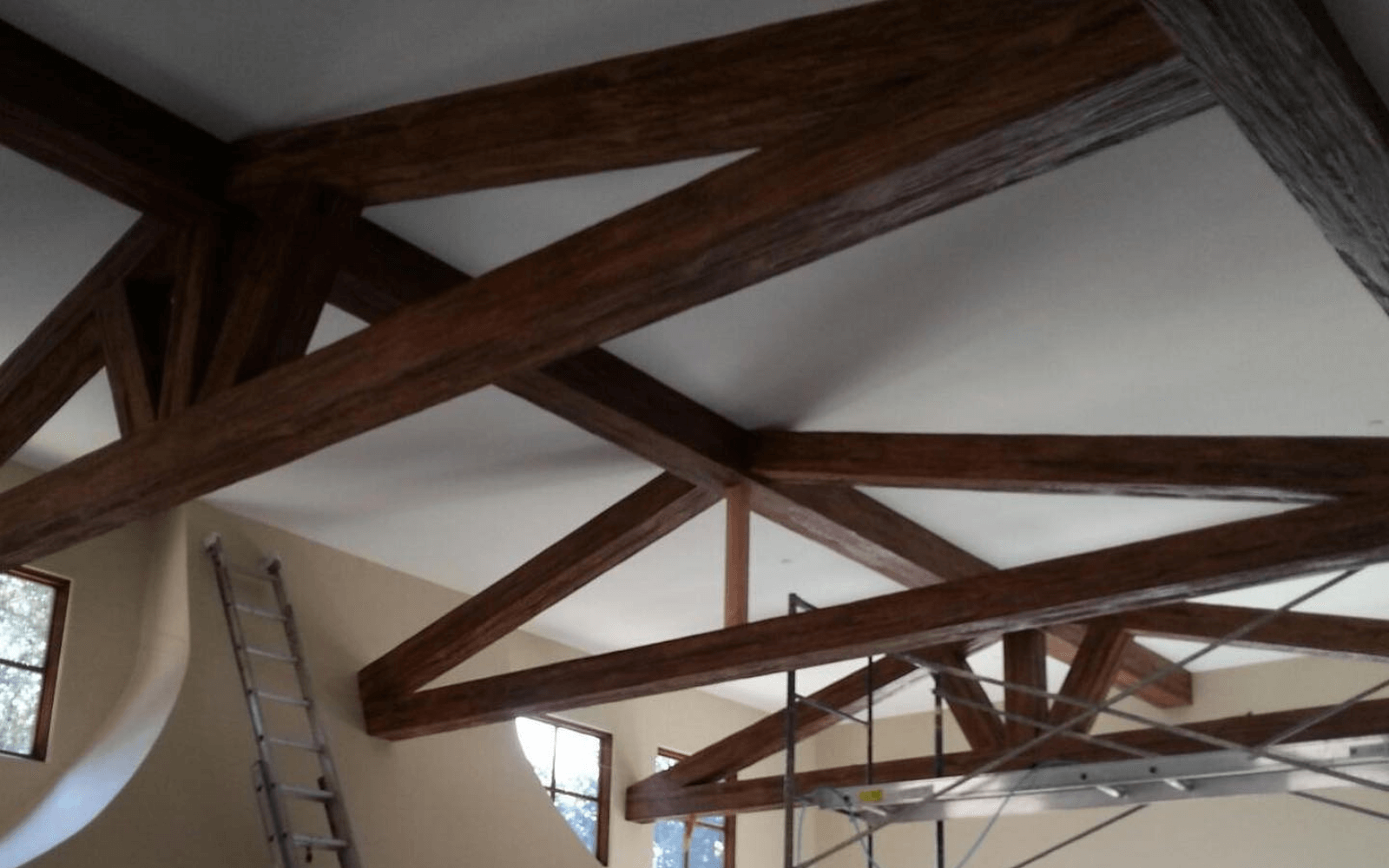 Dark stained rustic faux trusses over a vaulted ceiling