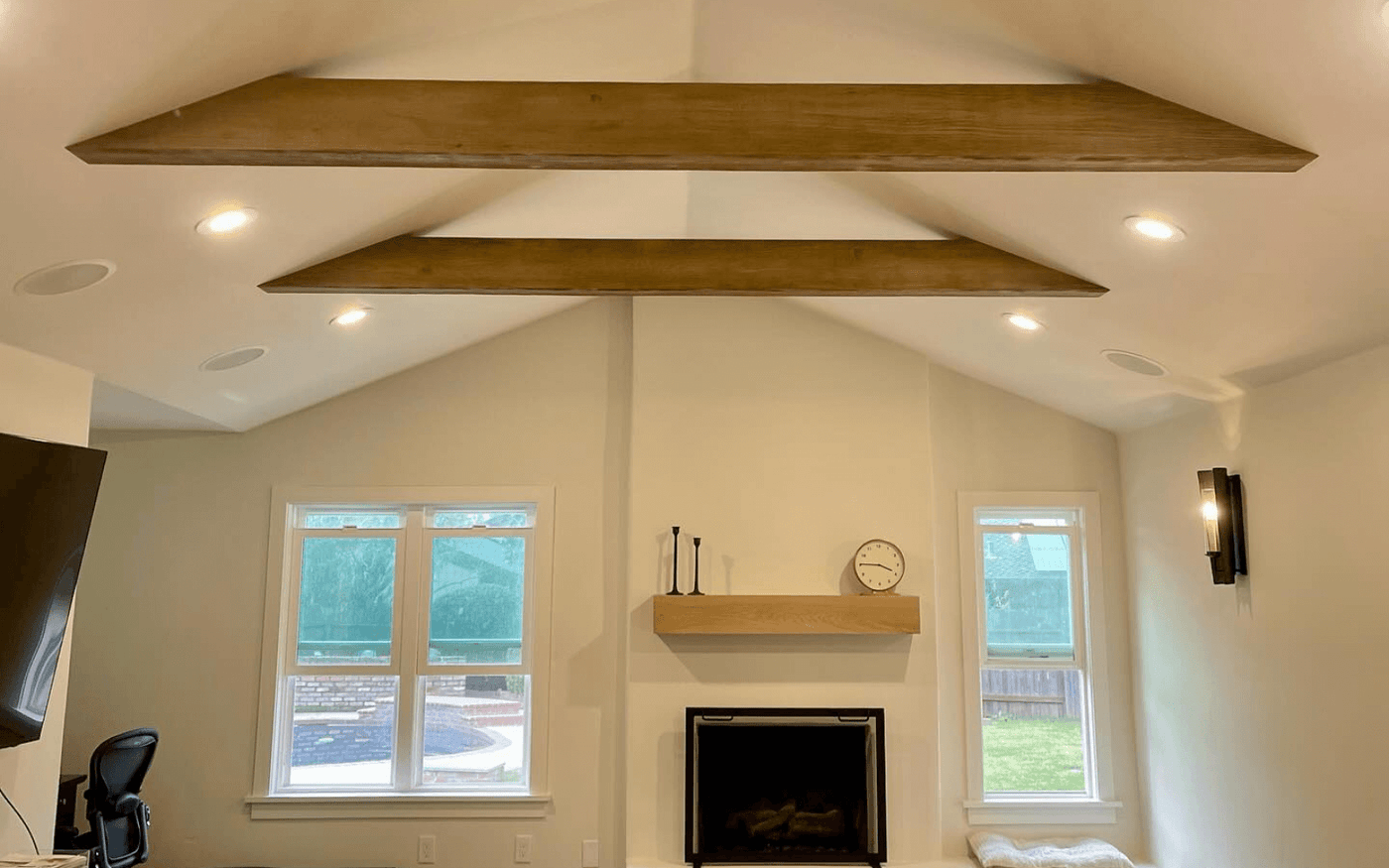 Vaulted living room ceiling with two parallel decorative beams above a stone fireplace
