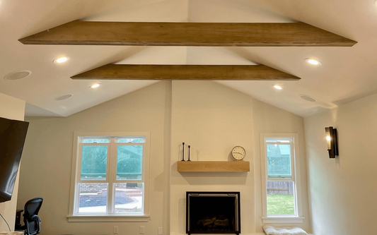 Vaulted living room ceiling with two parallel decorative beams above a stone fireplace