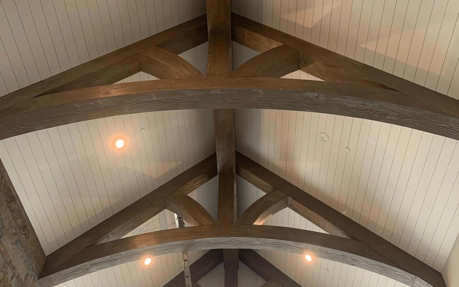 Arched faux truss under a boarded barrel-vaulted ceiling