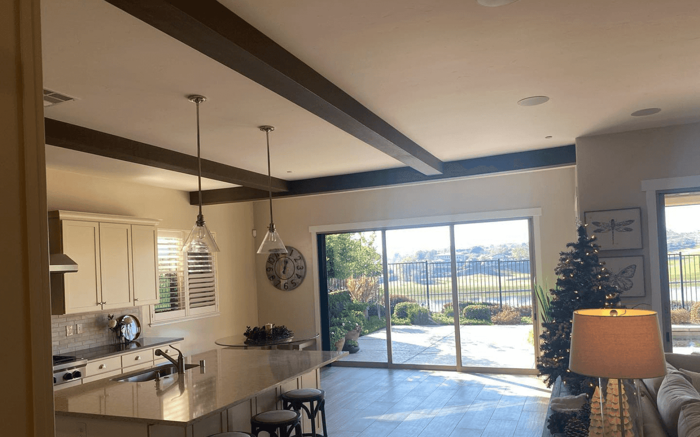 Open-plan kitchen and living room with a grid of decorative ceiling beams and pendant lighting over the island