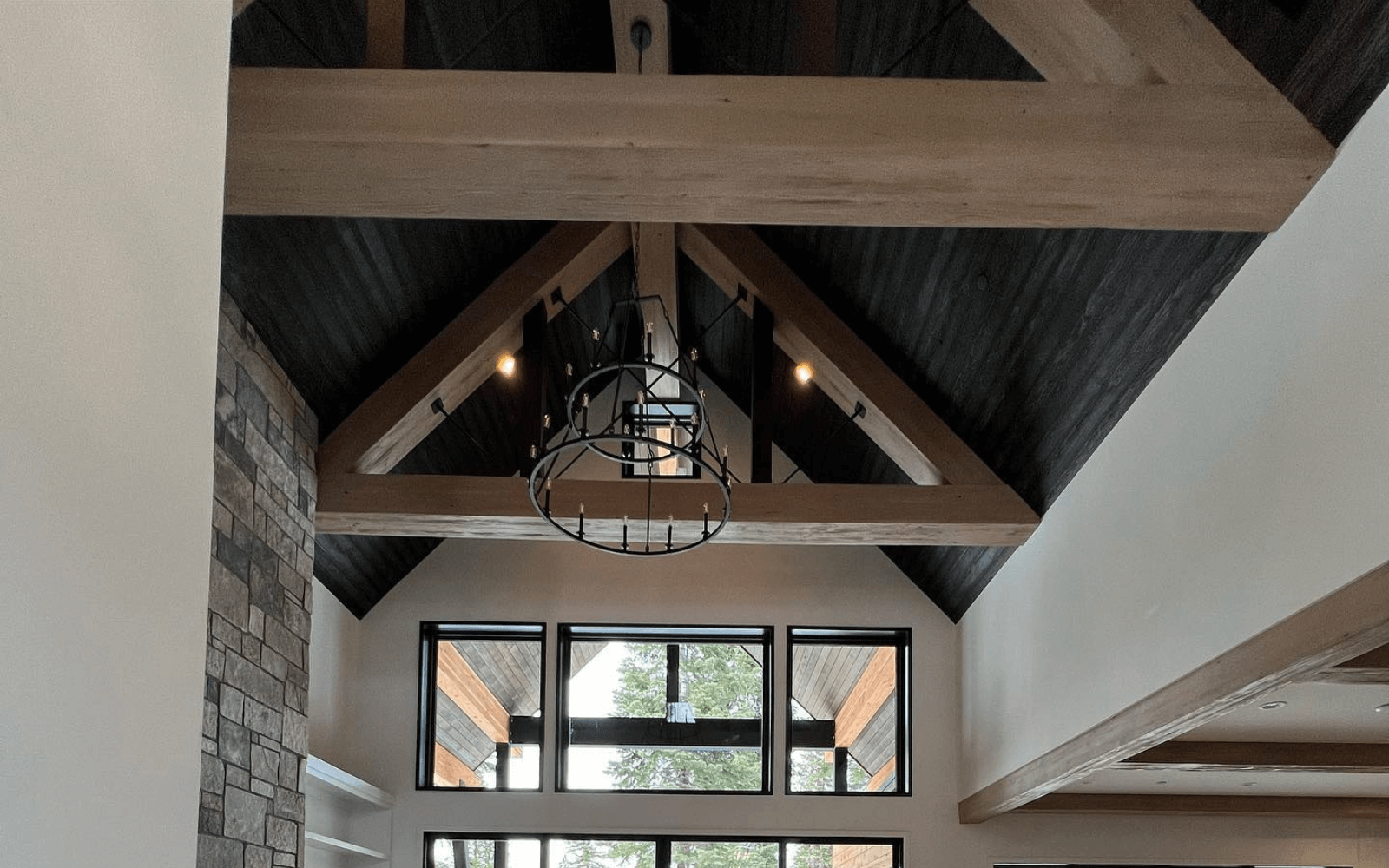 Faux trusses in a mountain modern great room with stone and a dark ceiling
