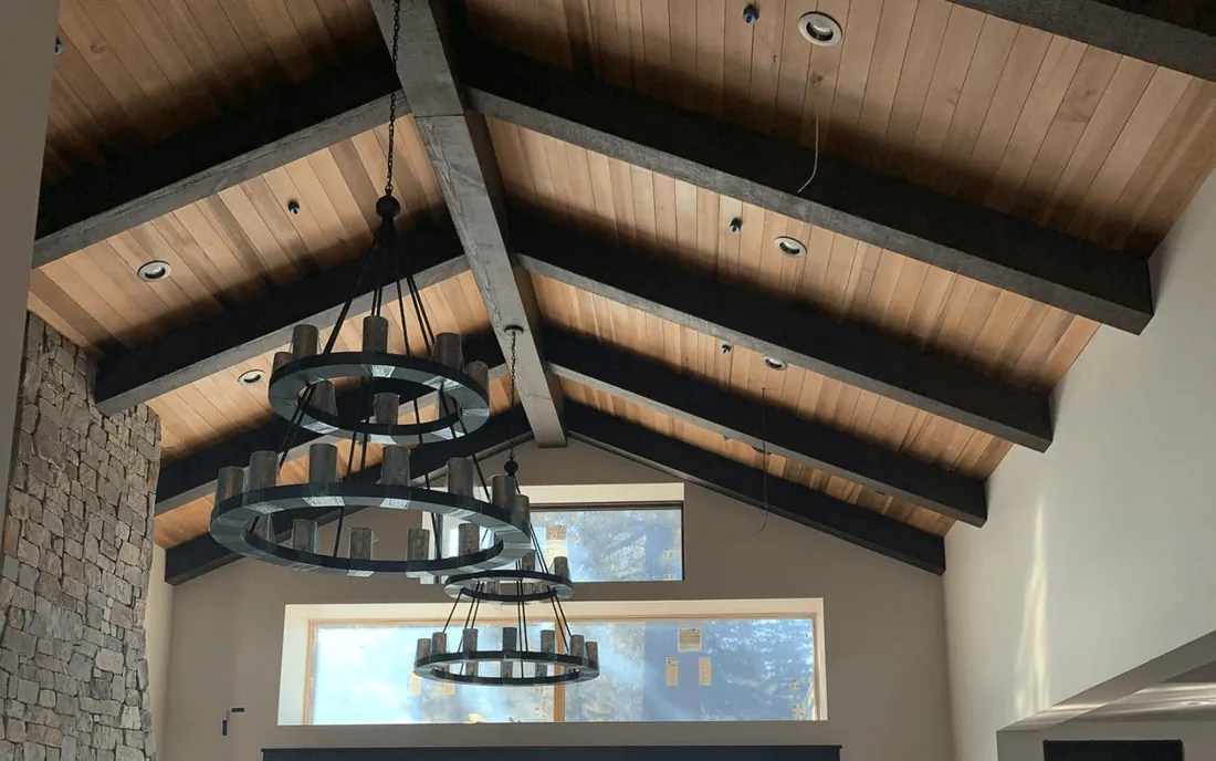 Vaulted ceiling with faux wood beams, a wood plank ceiling and a round chandelier